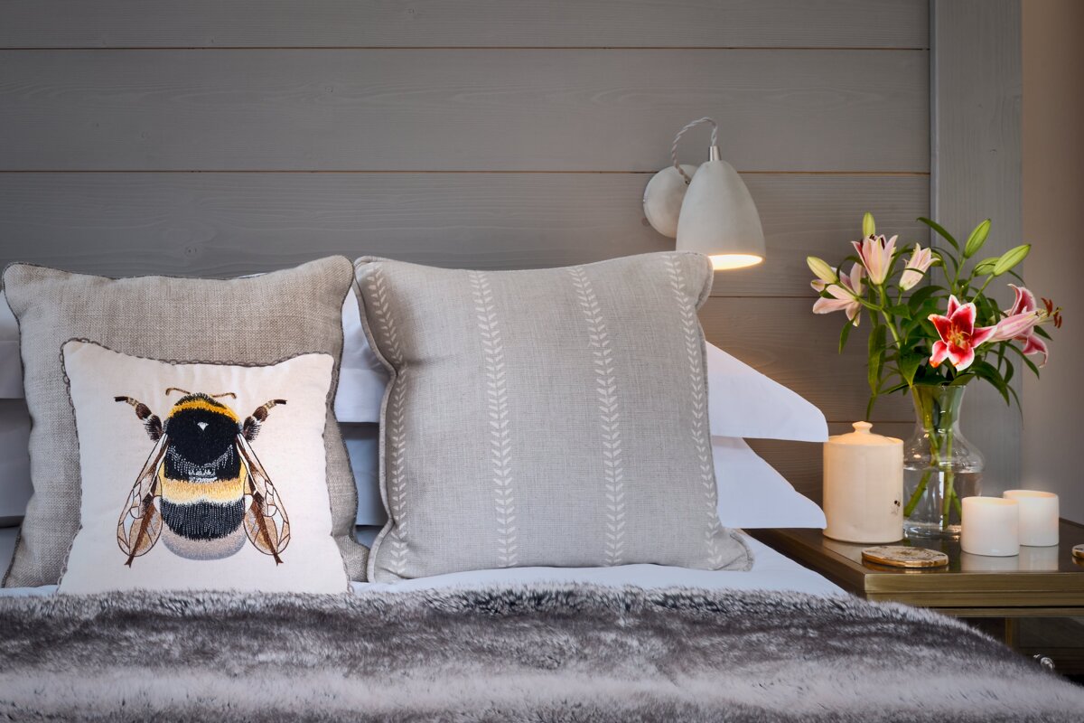 A bed with a pillow with a bee on it