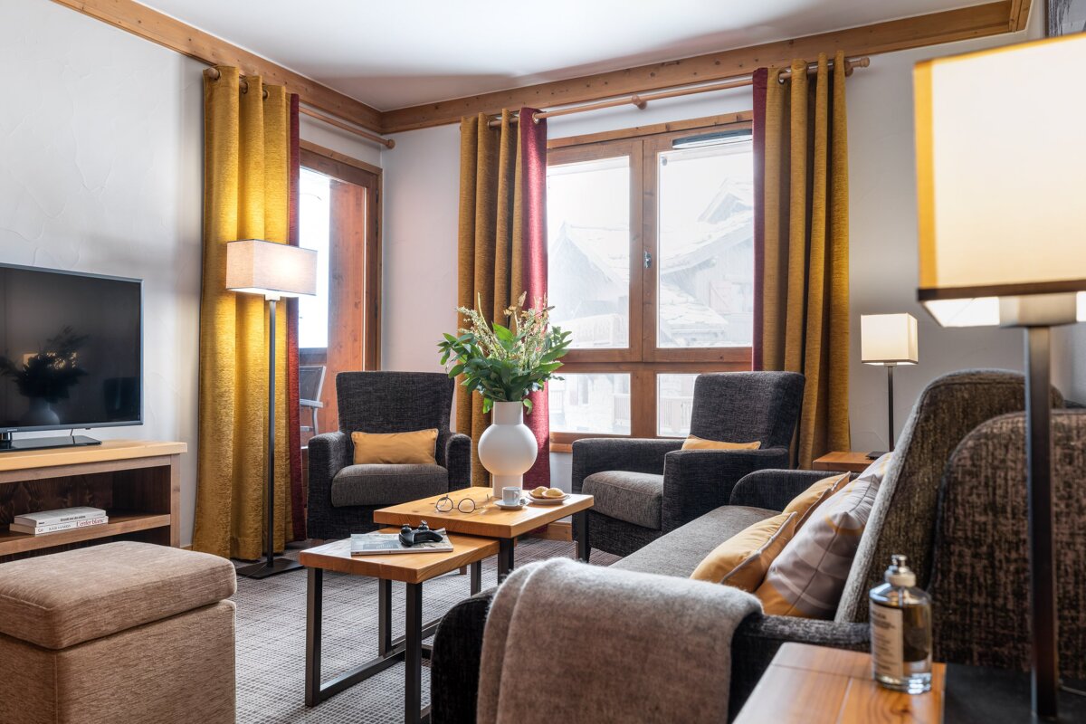 A living room with a couch two chairs and a flat screen tv