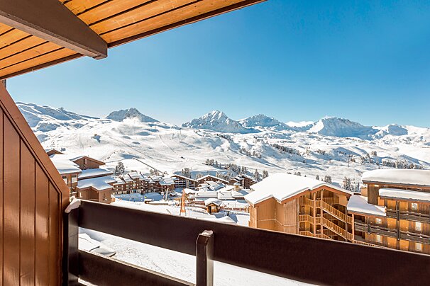A balcony overlooking a snowy ski resort with mountains in the background