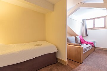 A small bedroom with a bed and a couch