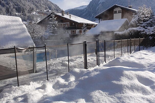 A fence surrounds a swimming pool in the snow