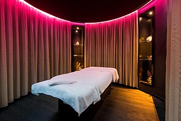 A massage table in a room with pink curtains