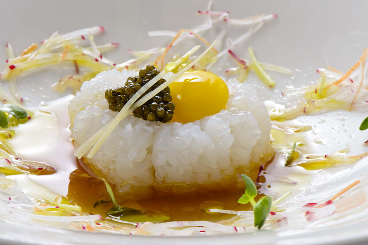 A plate of food with rice and a yellow egg on top