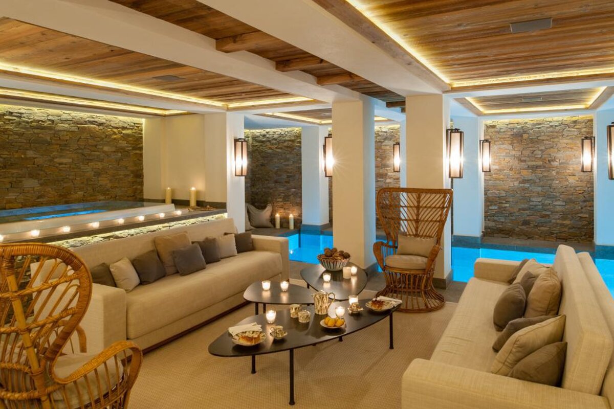A living room with a couch and wicker chairs next to a pool