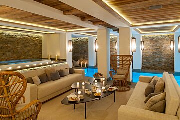 A living room with a couch and wicker chairs next to a pool