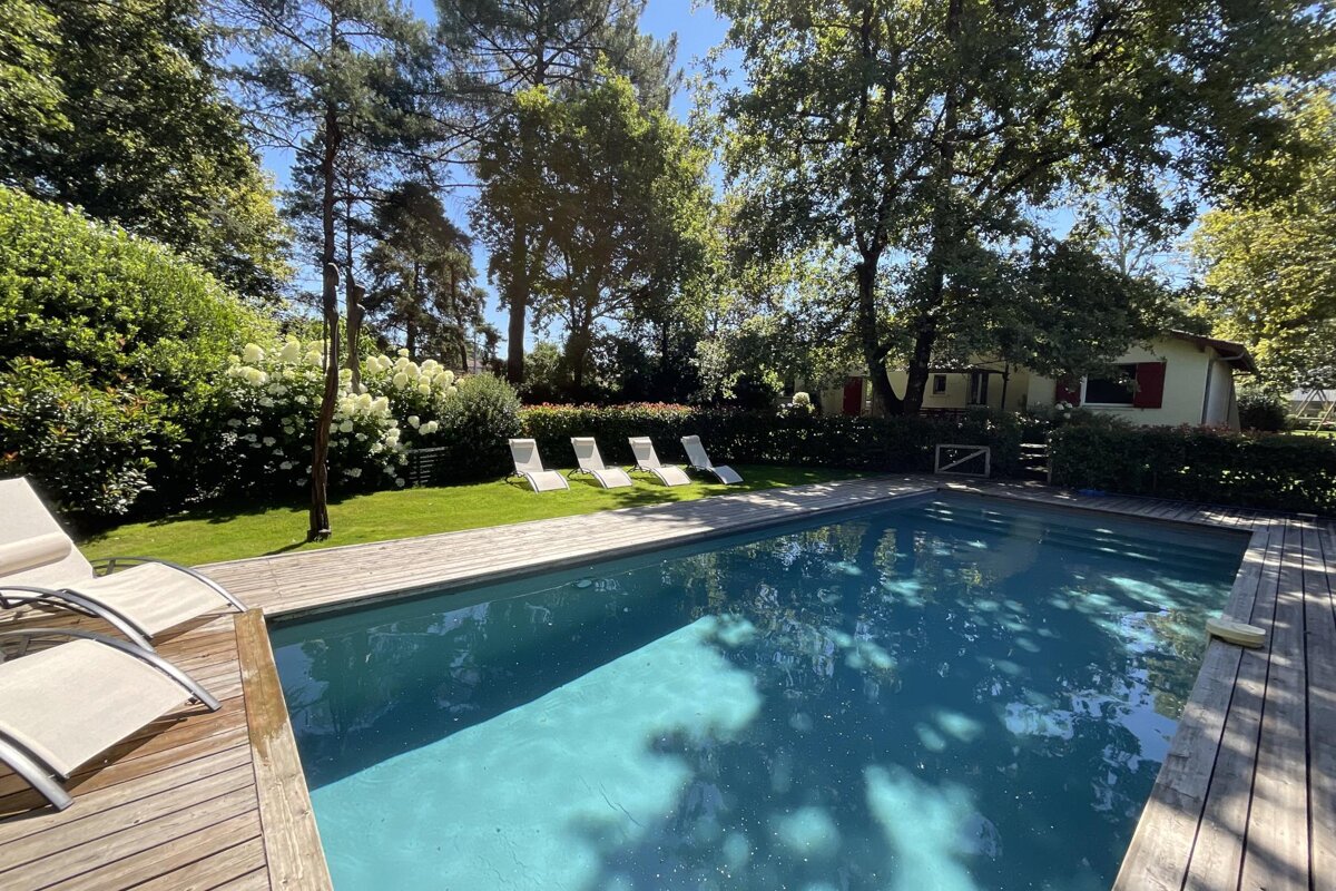 A large swimming pool surrounded by chairs and trees