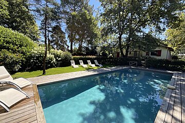 A large swimming pool surrounded by chairs and trees