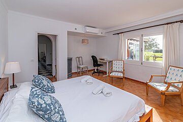 A bedroom with a large bed and two chairs