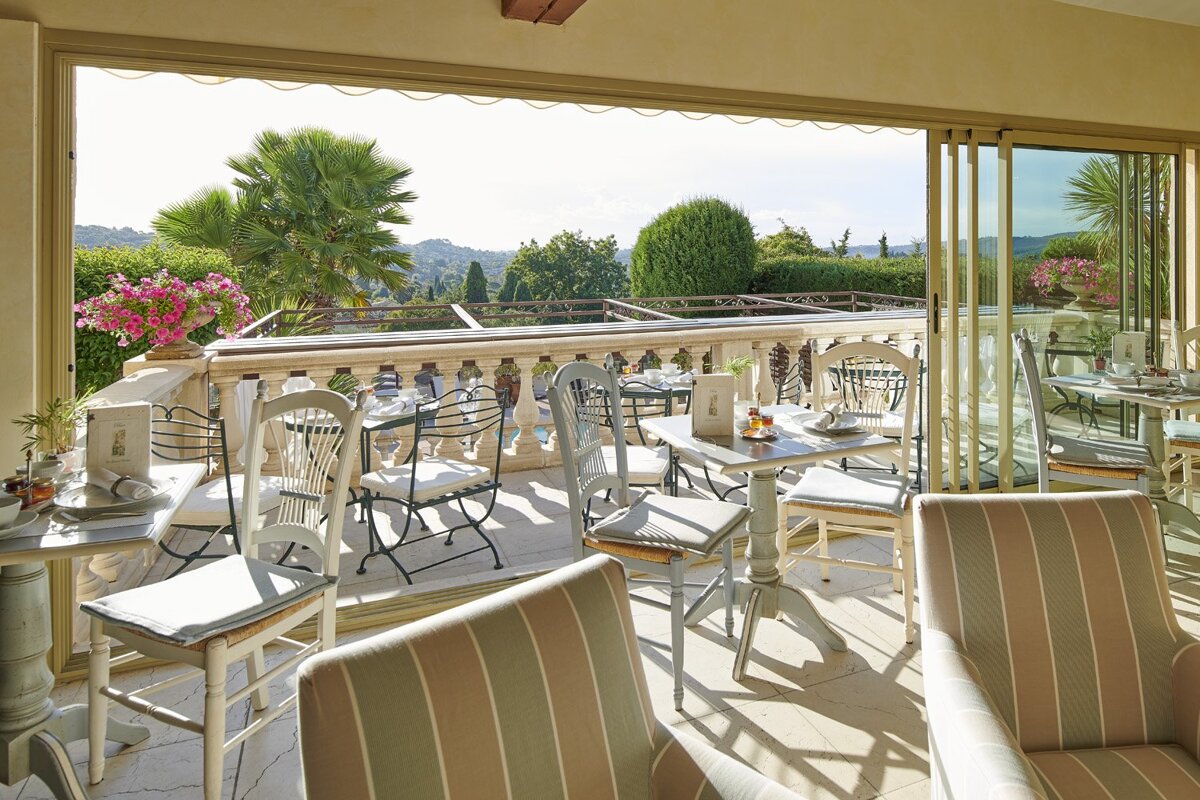 Tables and chairs on a balcony with a view of the mountains