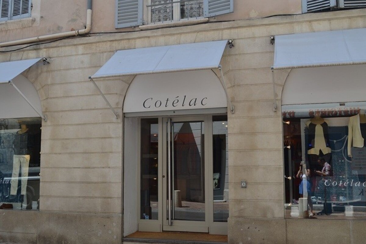 image of the shop front of cotelac in avignon, brick exterior with grey canopy.