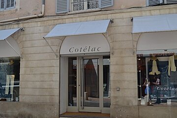 image of the shop front of cotelac in avignon, brick exterior with grey canopy.