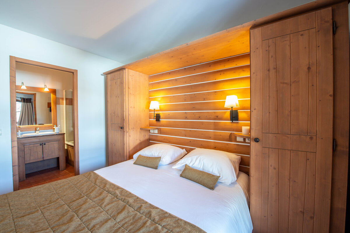 A bedroom with a wooden wall and a bed