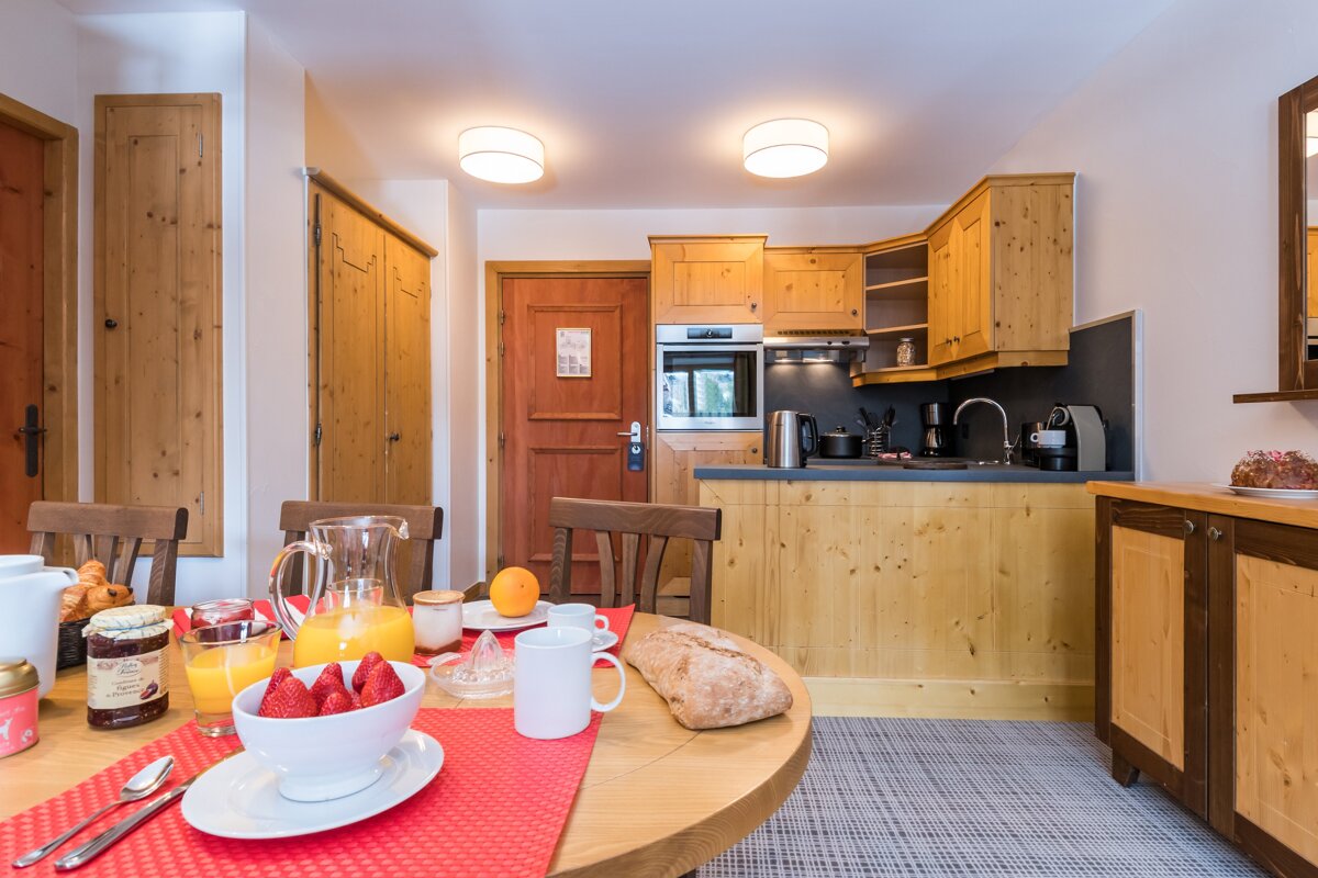 A bowl of strawberries sits on a table in a kitchen