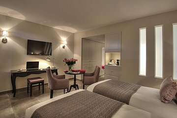 A hotel room with two beds a desk and a flat screen tv