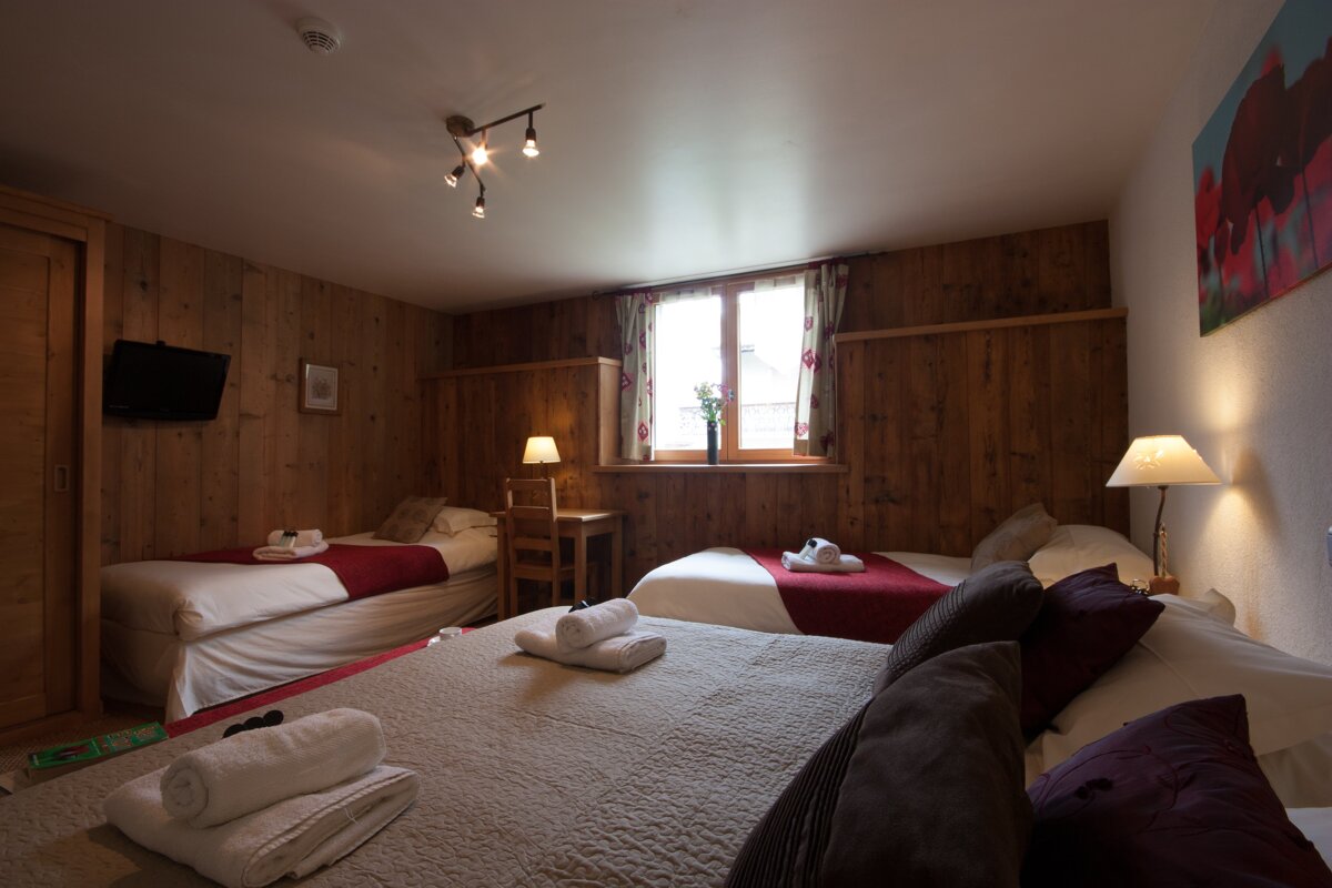 A hotel room with three beds and a desk