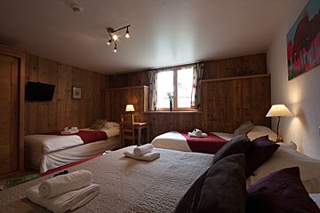 A hotel room with three beds and a desk