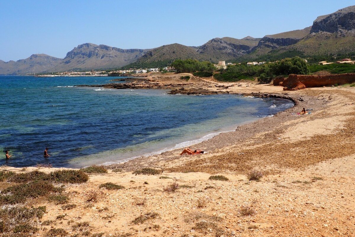 an empty beach with 2 people on the sand
