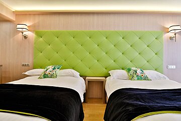 Two beds in a hotel room with a green headboard
