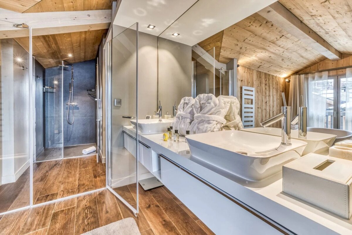 A bathroom with two sinks and a walk in shower