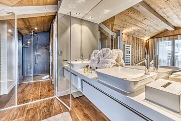 A bathroom with two sinks and a walk in shower