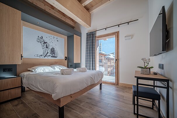 A bedroom with a leopard painting on the wall above the bed
