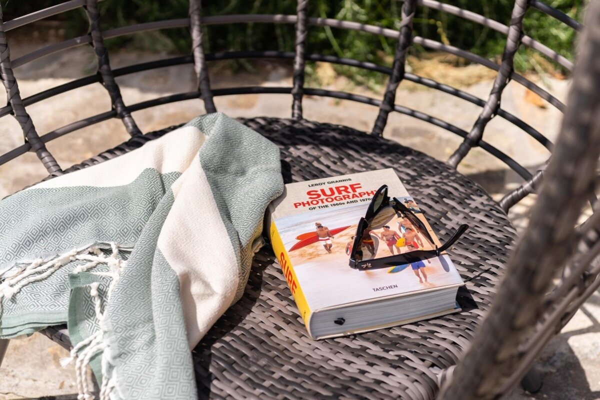 A book titled surf photography sits on a wicker chair