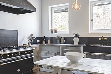 A kitchen with a black stove and a white bowl on the table