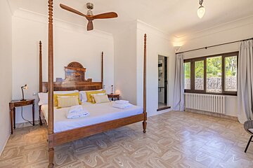 A bedroom with a four poster bed and a ceiling fan