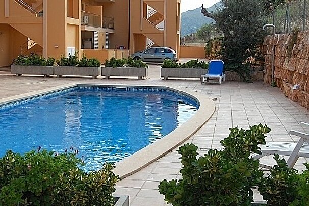 A blue car is parked next to a swimming pool