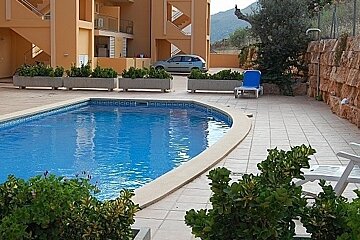 A blue car is parked next to a swimming pool