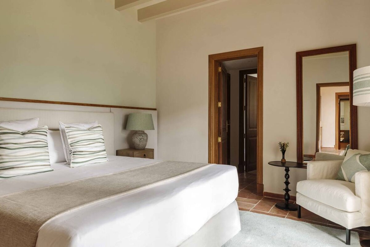 A bedroom with a large bed and a chair