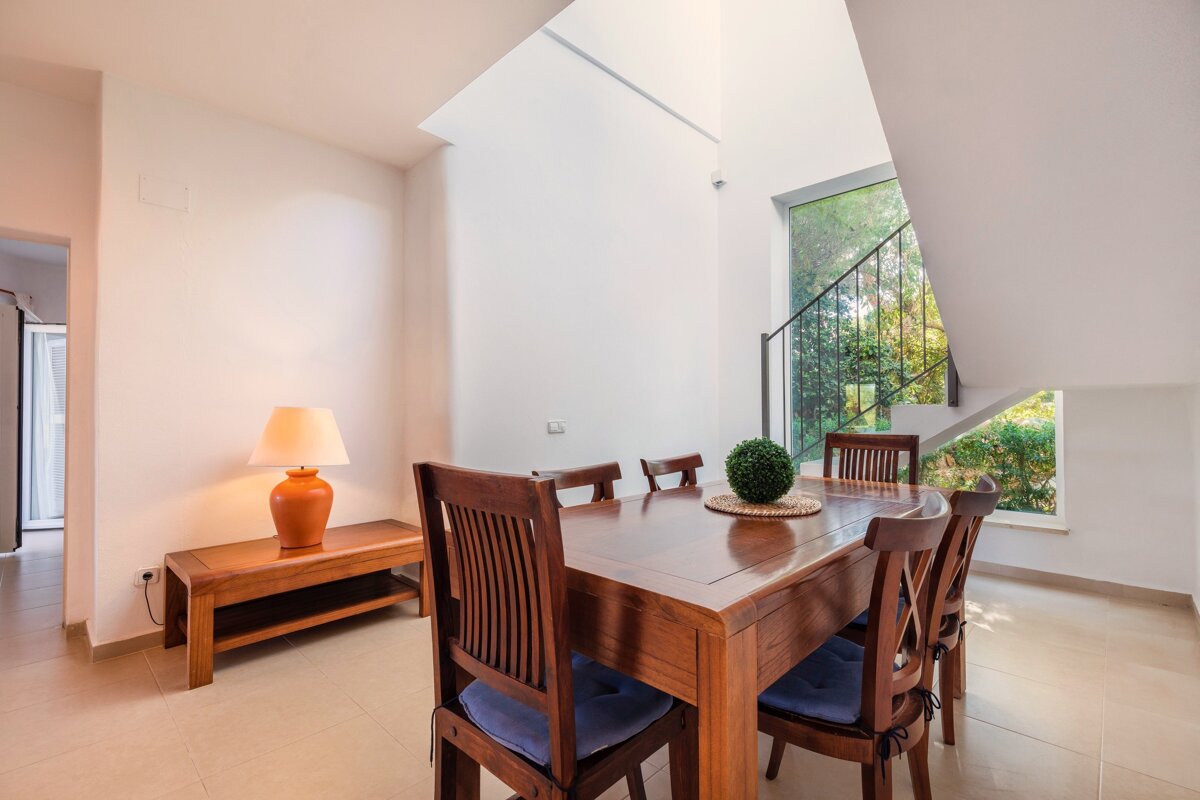 A dining room with a table and chairs and a lamp