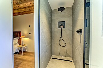 A bathroom with a shower and a shelf with bottles on it