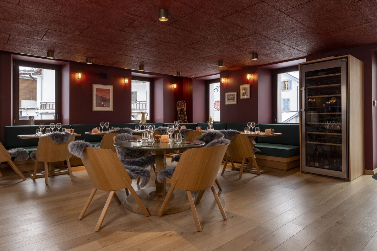 A dining room with a round table and red chairs