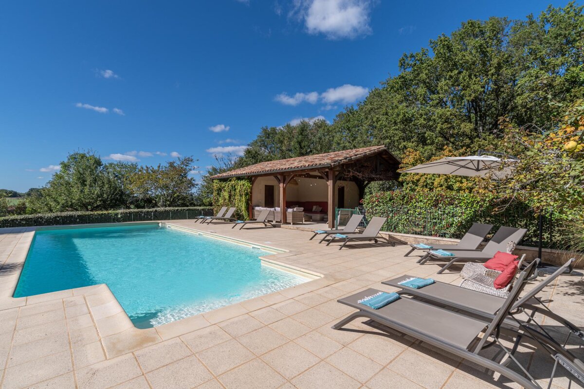 A large swimming pool surrounded by lounge chairs and umbrellas