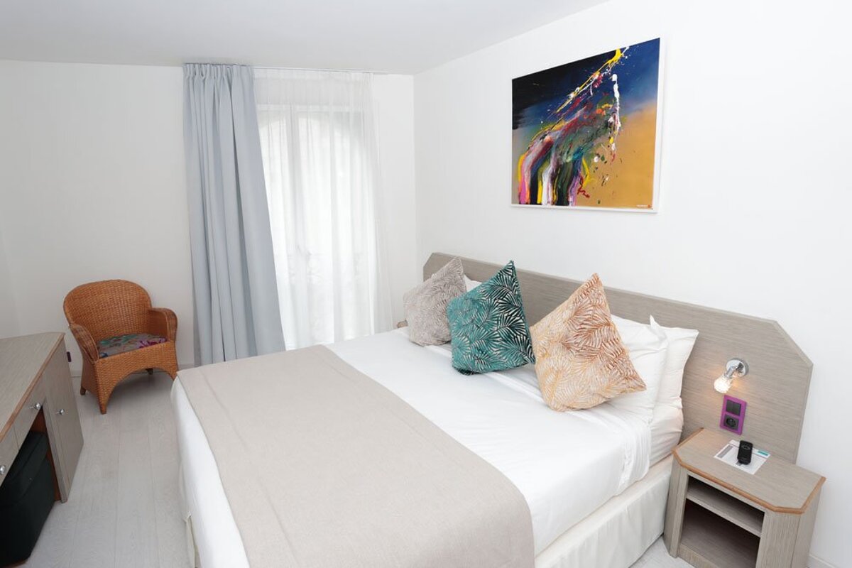 A hotel room with a large bed and a chair