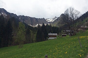 A house in the middle of a field with mountains in the background