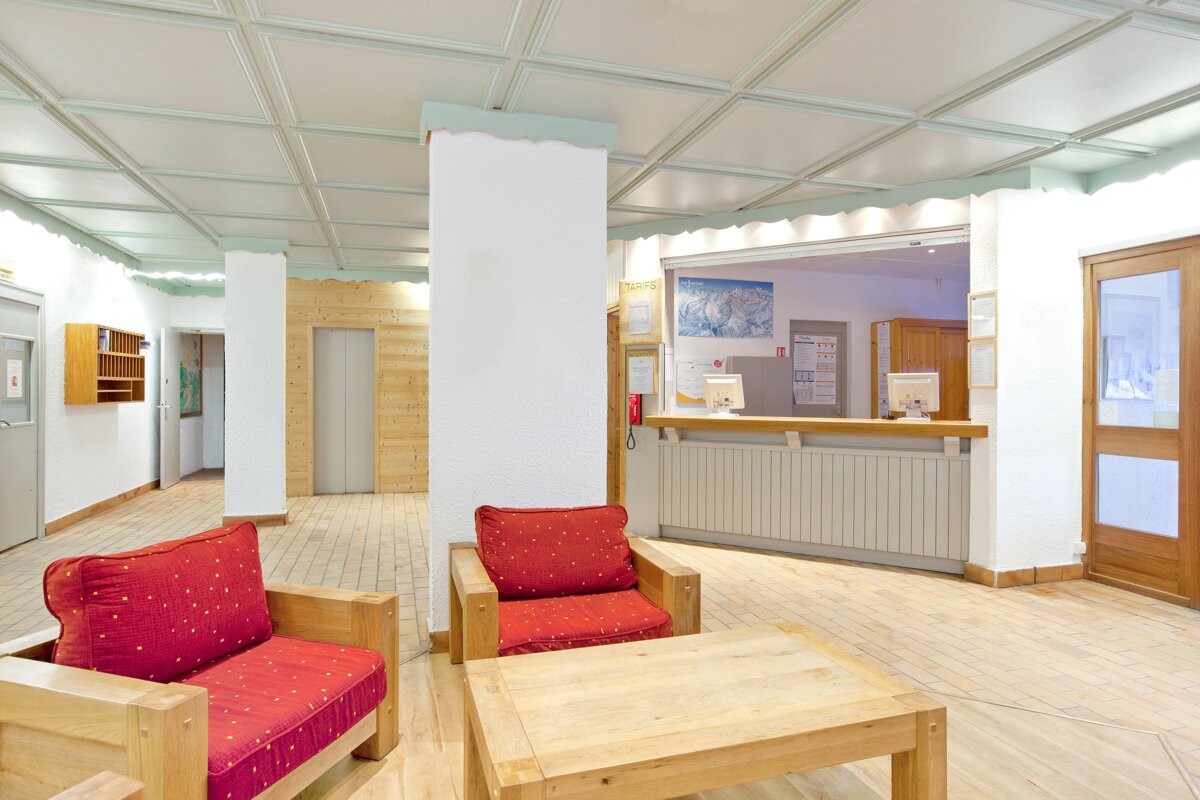 A hotel lobby with red chairs and a wooden table