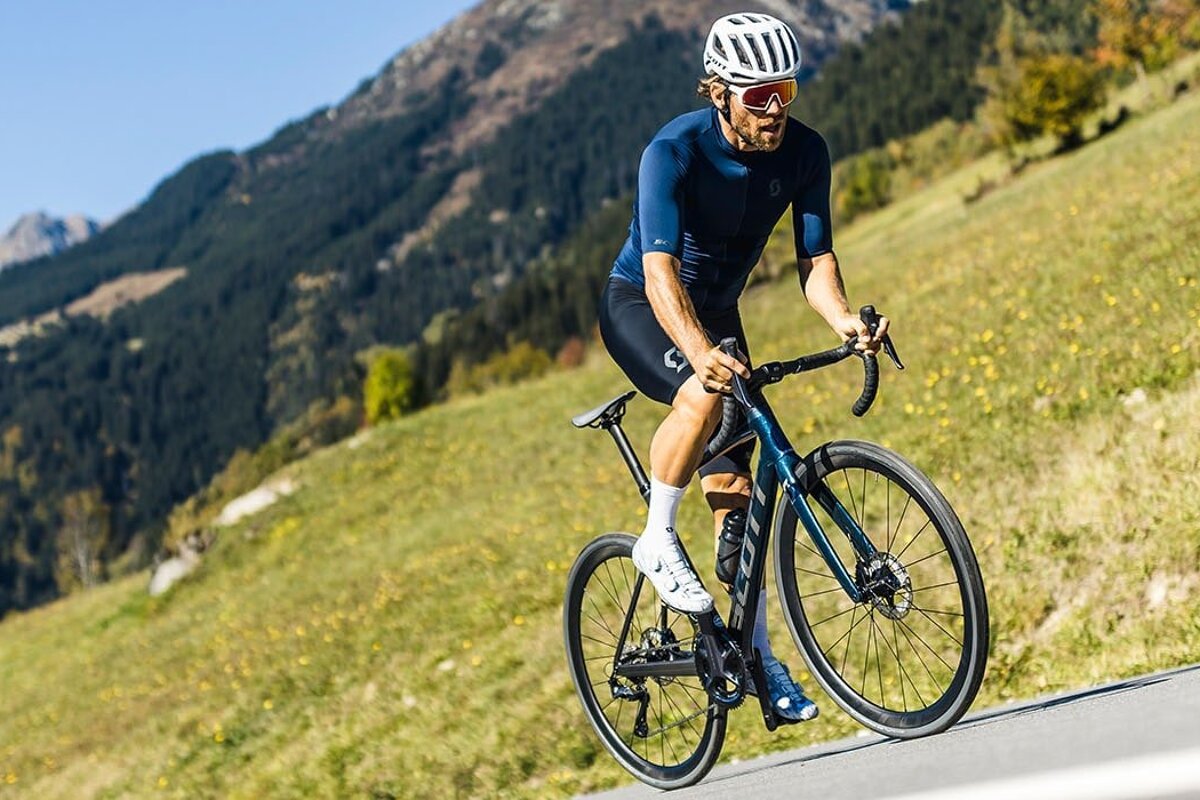 A man wearing a helmet and sunglasses is riding a bike