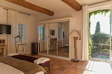 A bedroom with a large mirrored wardrobe and a large window