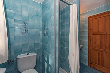 A bathroom with blue tiles and a toilet