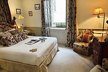 A bedroom with a bed a chair and a window