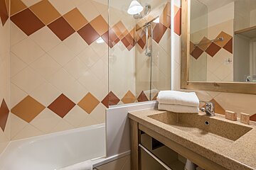 A bathroom with brown and white tiles and a sink
