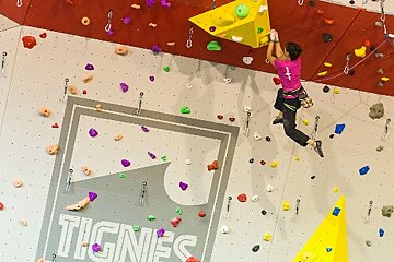 A person is climbing a wall with a sign that says tignes