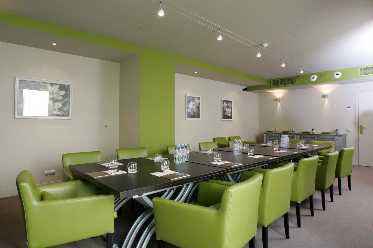 A conference room with a long table and green chairs