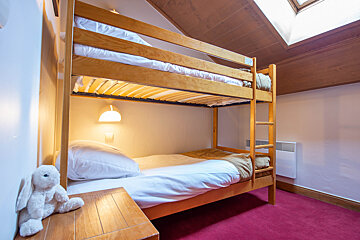 A bunk bed in a bedroom with a teddy bear on a nightstand