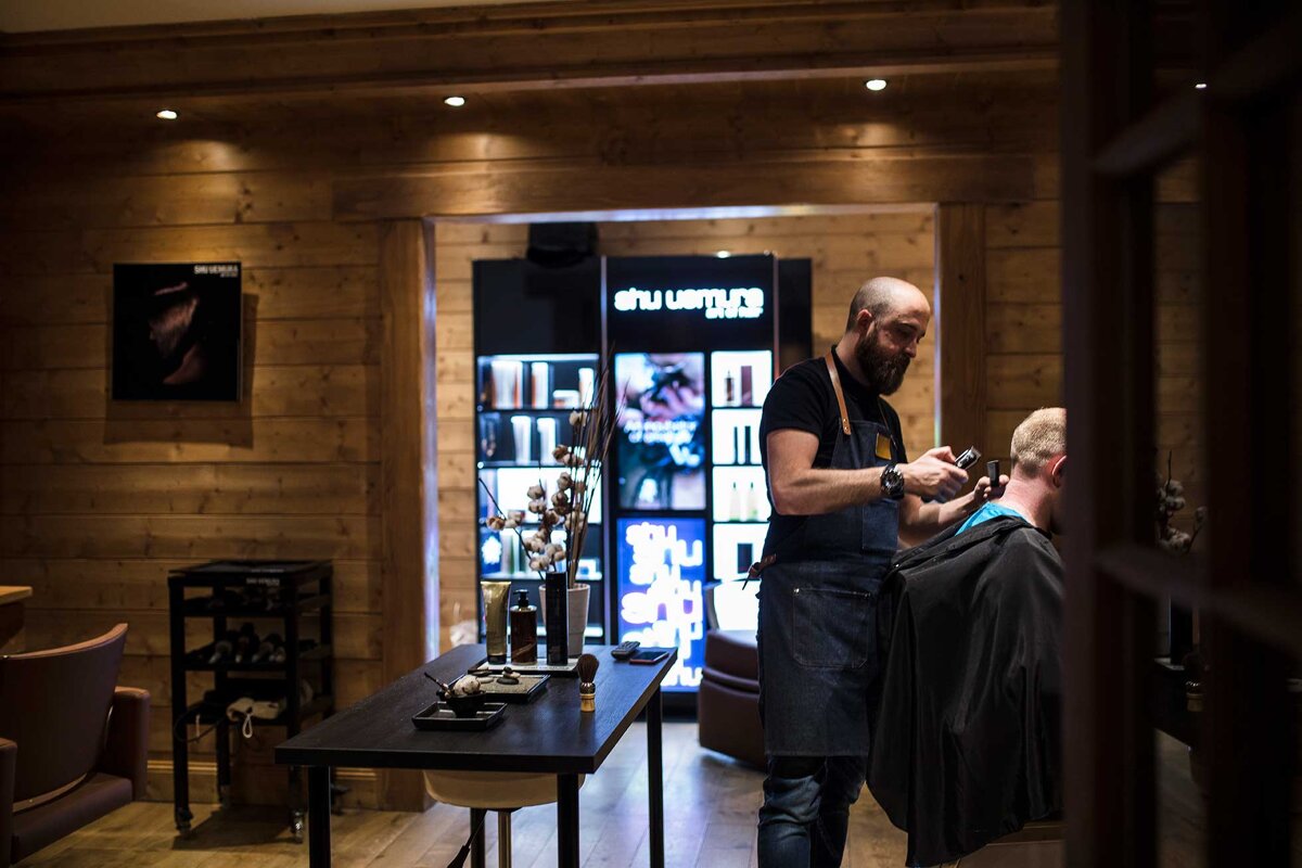 A man is getting his hair cut in front of a shu uemura store