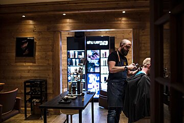 A man is getting his hair cut in front of a shu uemura store