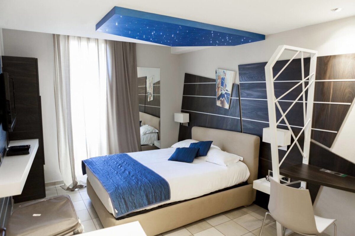 A hotel room with a bed and a blue ceiling
