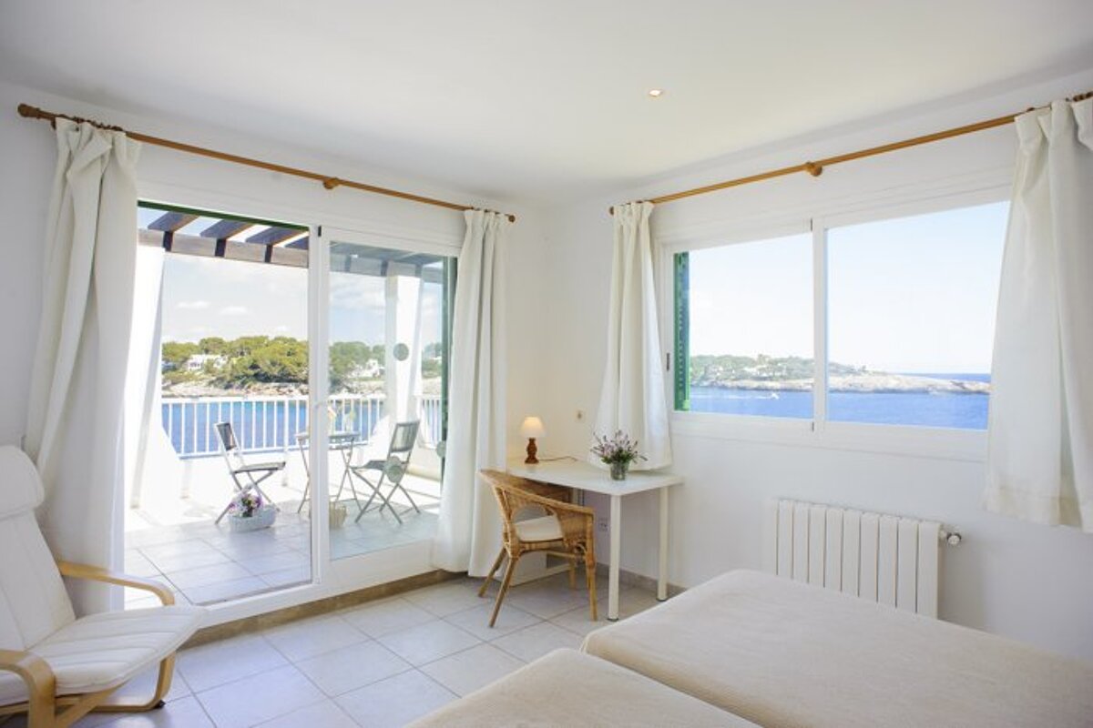 A bedroom with a sliding glass door leading to a balcony overlooking the ocean